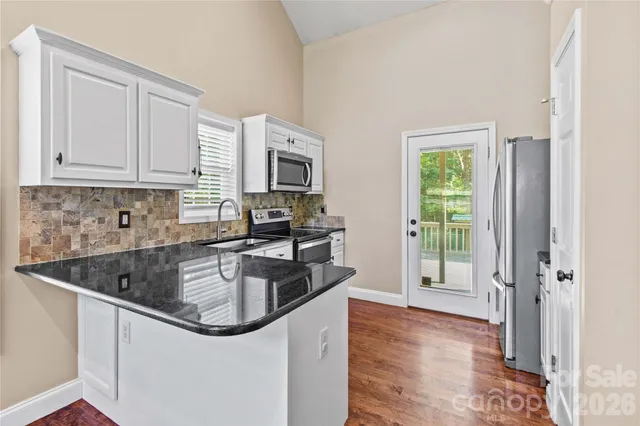 a kitchen with stainless steel appliances granite countertop a sink a stove and a refrigerator
