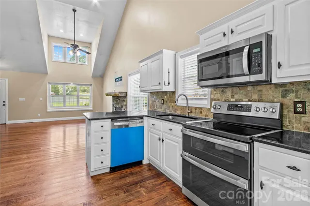 a kitchen with stainless steel appliances granite countertop a stove microwave and sink