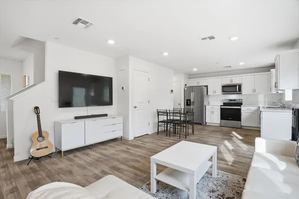 a living room with furniture a flat screen tv and kitchen view