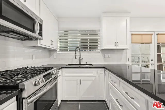 a kitchen with granite countertop a sink stove and cabinets