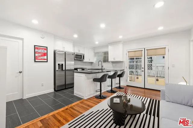 a living room with stainless steel appliances furniture a rug and a view of kitchen