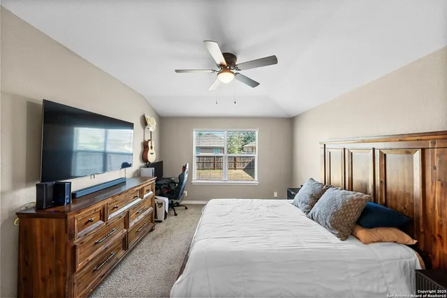 a large bedroom with a bed and a flat tv screen on dresser
