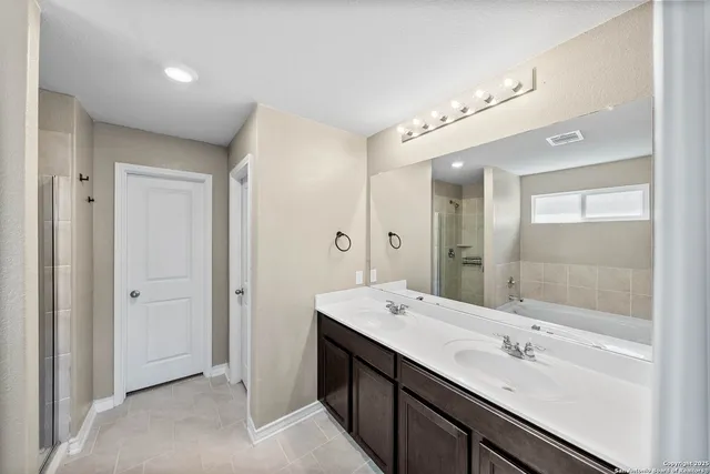a bathroom with a double vanity sink mirror and shower