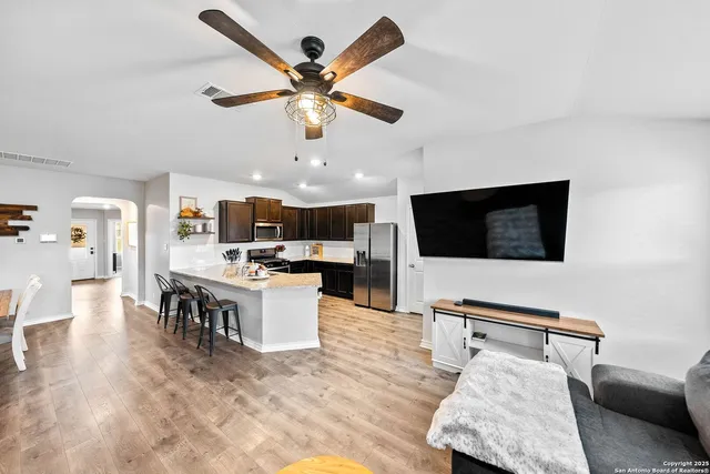 a living room with furniture kitchen view and a flat screen tv