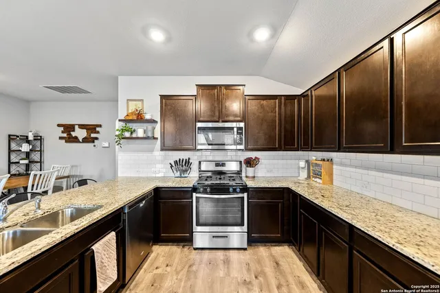a kitchen with stainless steel appliances granite countertop a sink stove and refrigerator