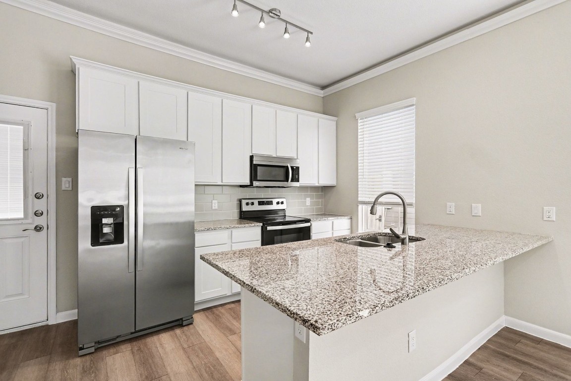 19602 Pradera Meadows Loop Rosharon, TX 77583 - Photo 11 of 47 a kitchen with stainless steel appliances granite countertop a sink a microwave a refrigerator and white cabinets