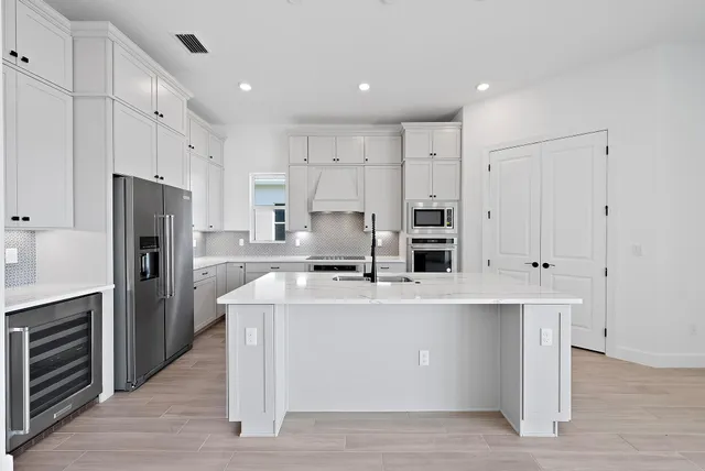 a large kitchen with stainless steel appliances a large counter top a stove and a refrigerator