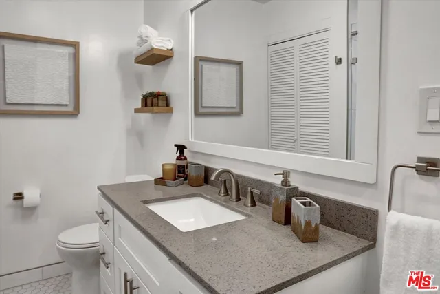 a bathroom with a granite countertop sink toilet and mirror