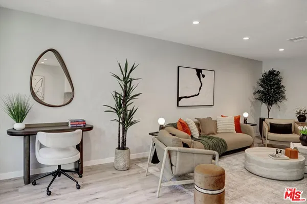 a living room with furniture a mirror and a potted plant