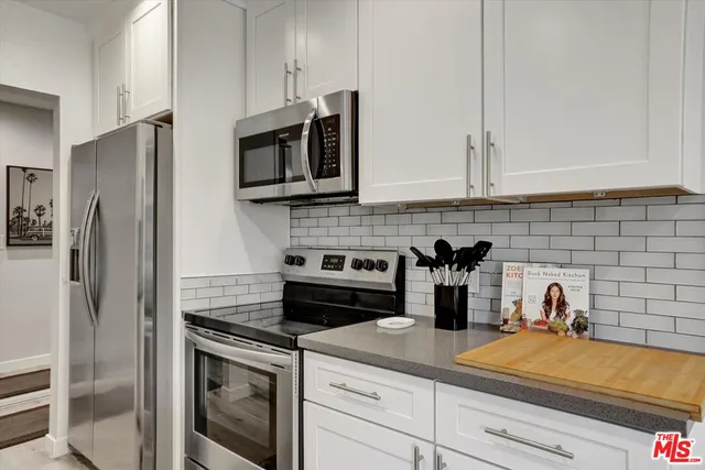 a kitchen with stainless steel appliances granite countertop white cabinets and a stove