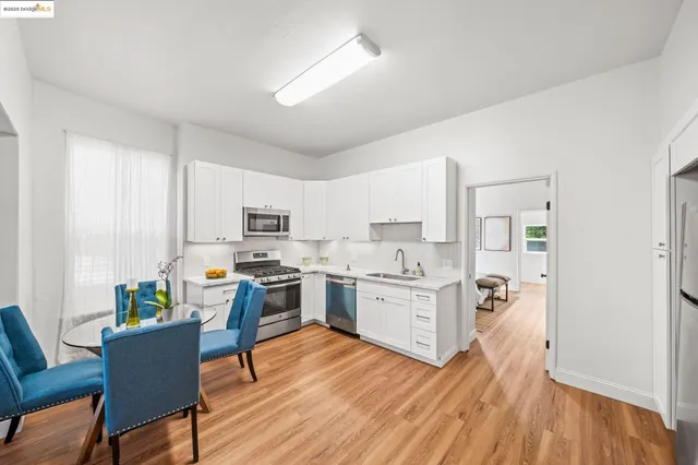 a kitchen with stainless steel appliances granite countertop a stove top oven a sink dishwasher and a refrigerator with wooden floor