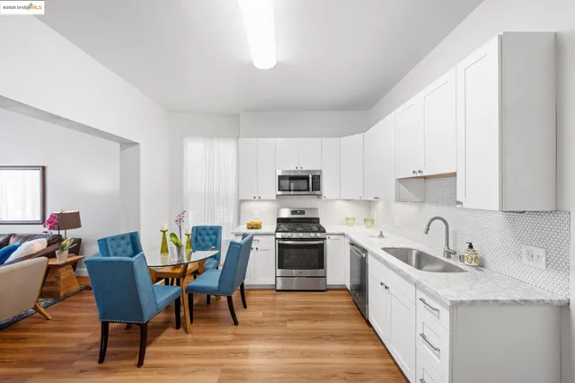 a open kitchen with stainless steel appliances granite countertop a stove top oven a sink dishwasher and a dining table with wooden floor