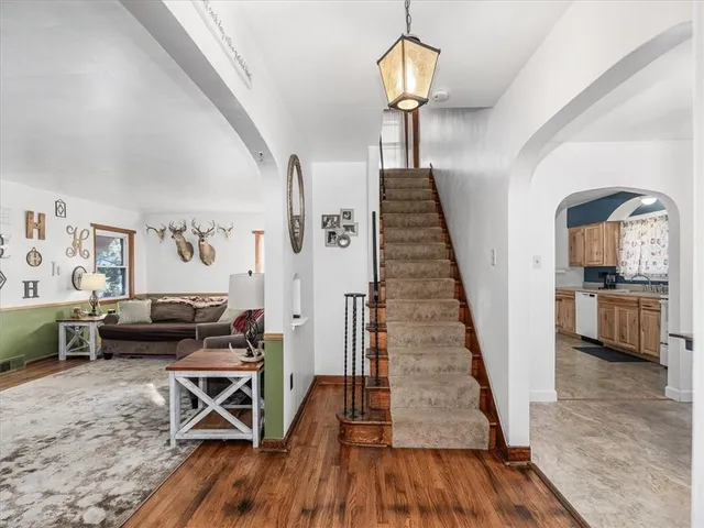 a view of a livingroom with furniture wooden floor windows and staircase