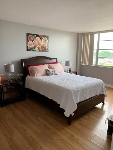a bedroom with a bed painting on wall and a large window