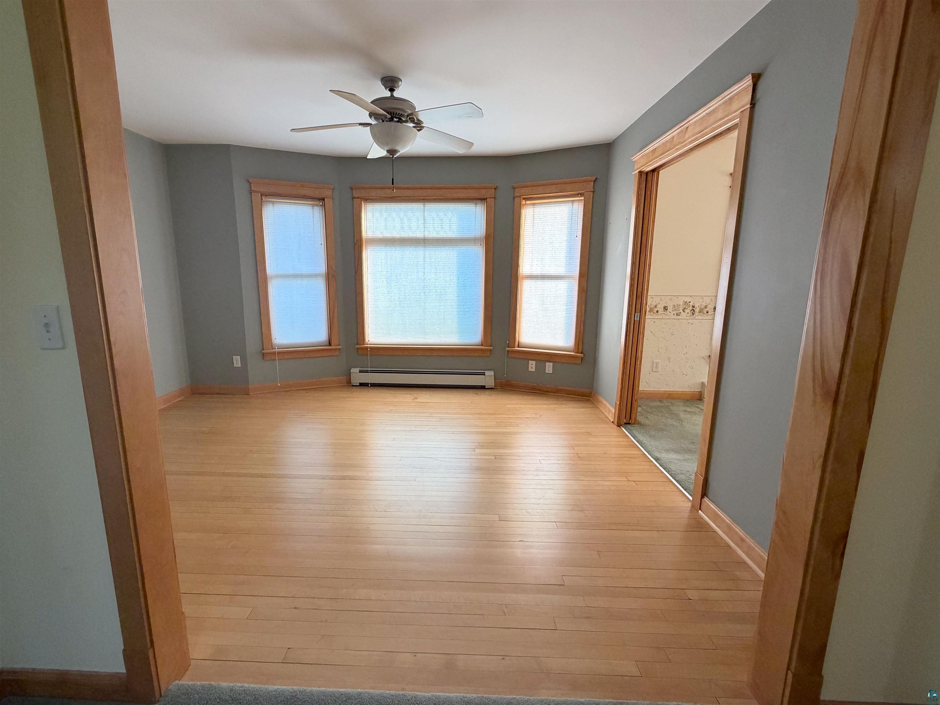 13 West 8th Street Duluth, MN 55806 - Photo 22 of 57 Hardwood flooring throughout a room with a bay window featuring three individual windows