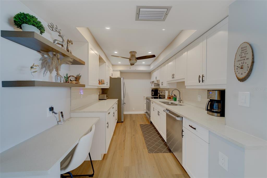 255 Dolphin Point, Unit 802 Clearwater Beach, FL 33767 - Photo 13 of 41 a large kitchen with stainless steel appliances lots of counter space and wooden floor