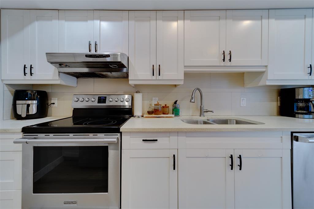 255 Dolphin Point, Unit 802 Clearwater Beach, FL 33767 - Photo 14 of 41 a kitchen with stainless steel appliances granite countertop a sink a stove and cabinets