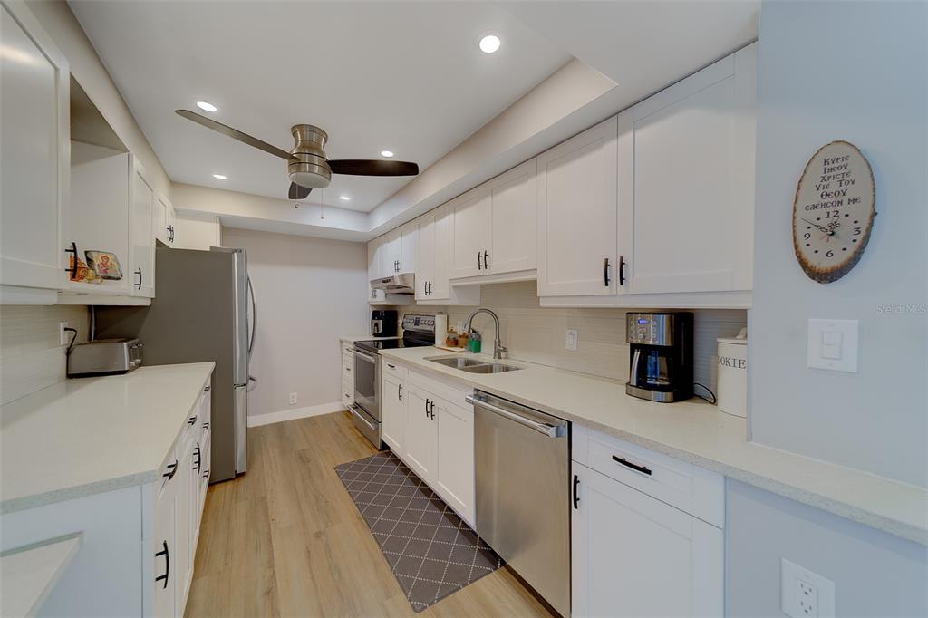255 Dolphin Point, Unit 802 Clearwater Beach, FL 33767 - Photo 15 of 41 a kitchen with a sink a clock and cabinets
