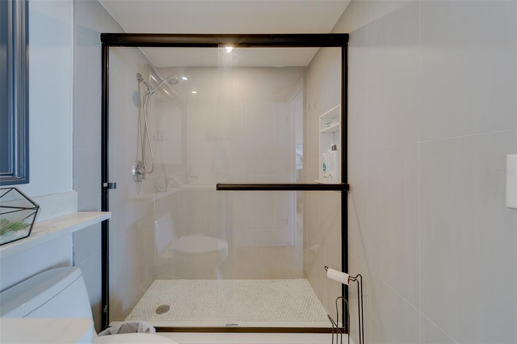 255 Dolphin Point, Unit 802 Clearwater Beach, FL 33767 - Photo 20 of 41 a bathroom with a glass shower door