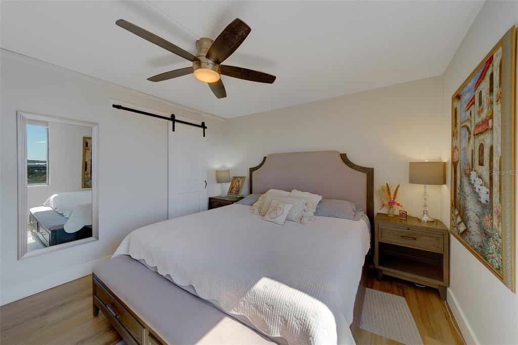 255 Dolphin Point, Unit 802 Clearwater Beach, FL 33767 - Photo 23 of 41 a bedroom with a bed and a chandelier