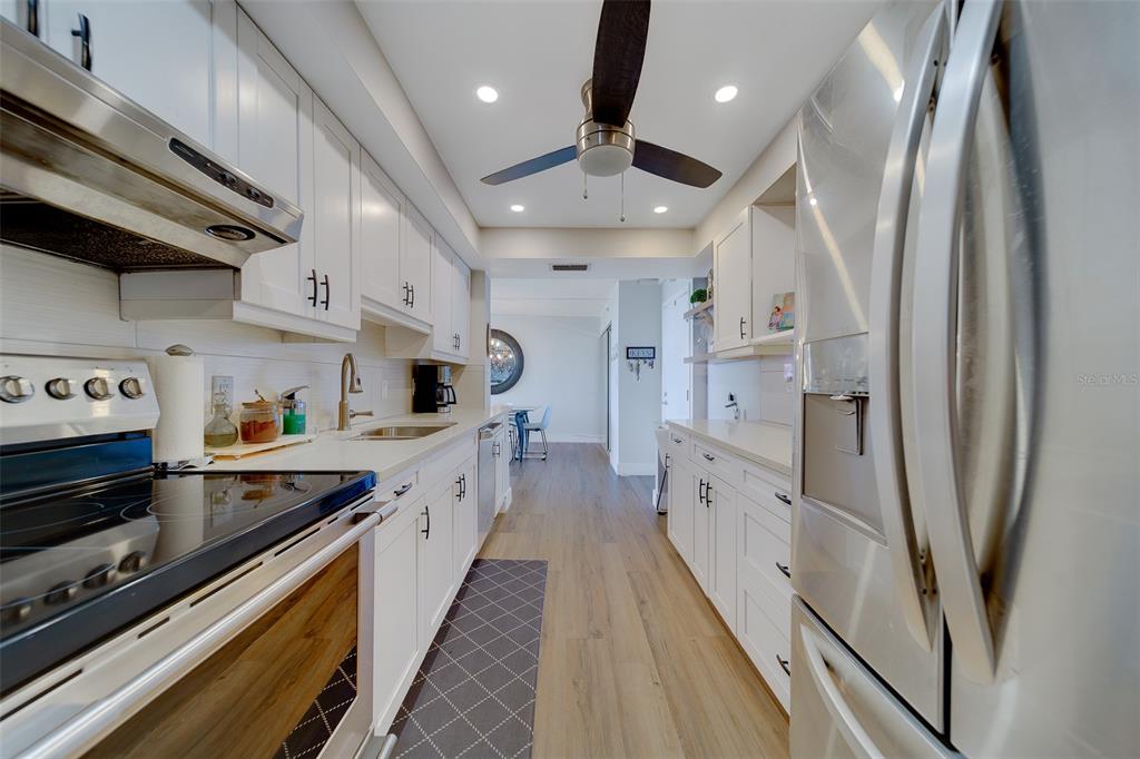 255 Dolphin Point, Unit 802 Clearwater Beach, FL 33767 - Photo 3 of 41 a large kitchen with stainless steel appliances a refrigerator a sink a stove and white cabinets