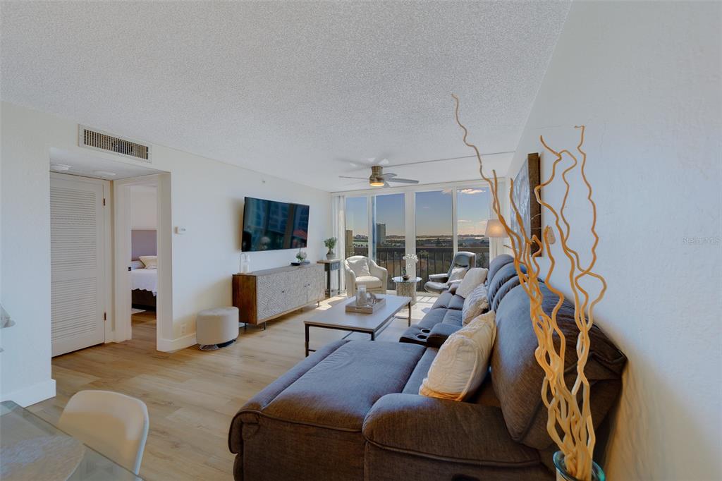 255 Dolphin Point, Unit 802 Clearwater Beach, FL 33767 - Photo 6 of 41 a living room with furniture and a flat screen tv