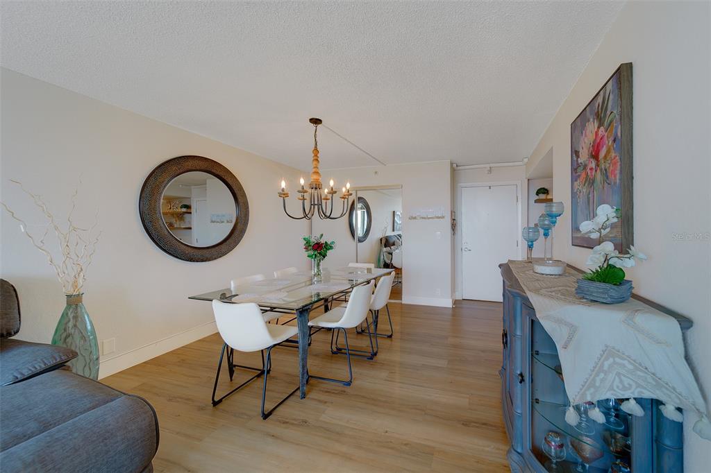 255 Dolphin Point, Unit 802 Clearwater Beach, FL 33767 - Photo 9 of 41 a view of a dining room with furniture and a chandelier