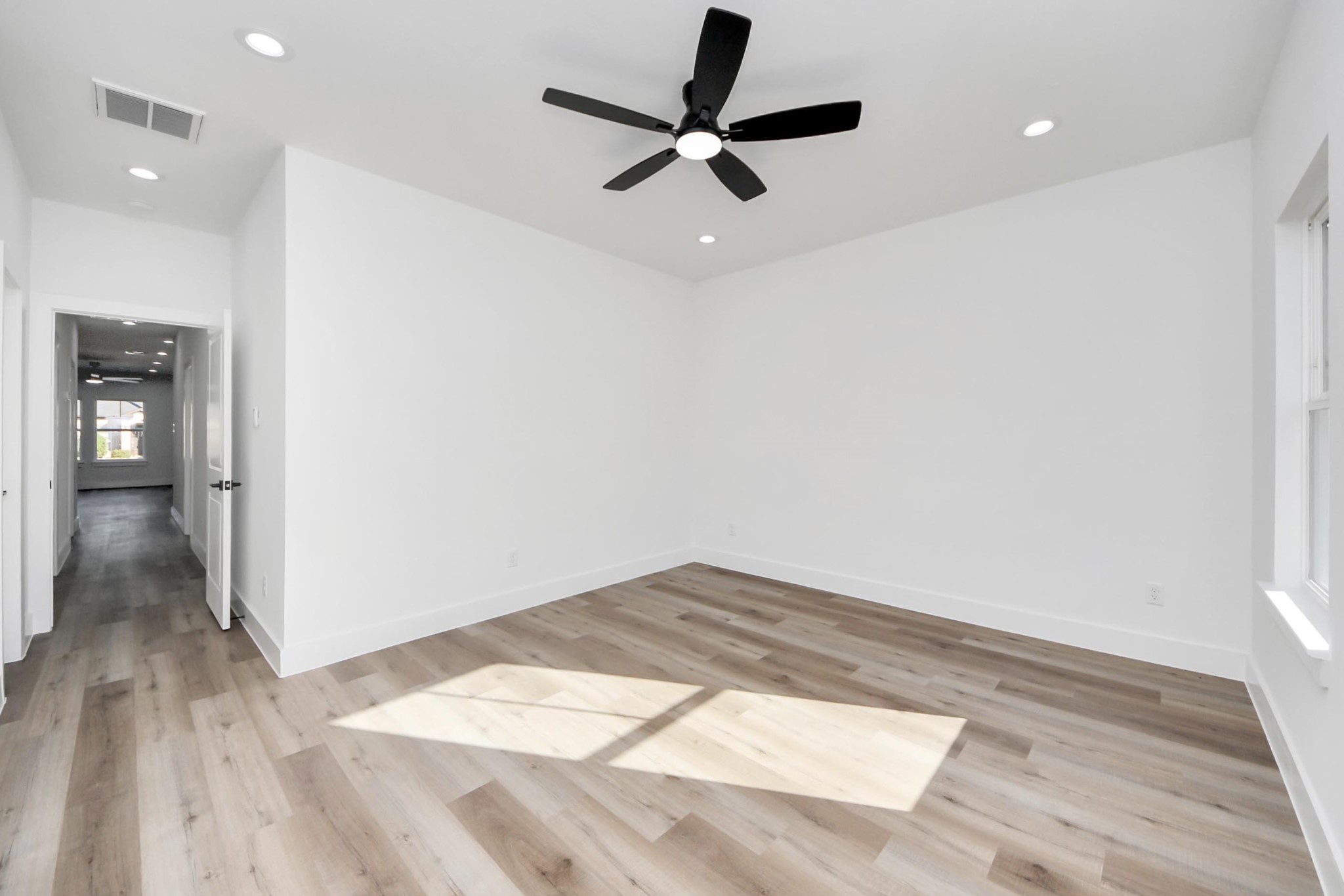 4606 Mallow Street Houston, TX 77051 - Photo 22 of 31 This primary bedroom features a bright, spacious area with light flooring, crisp white walls, and recessed lighting. A modern ceiling fan adds style and comfort, while ample natural light streams through large windows.