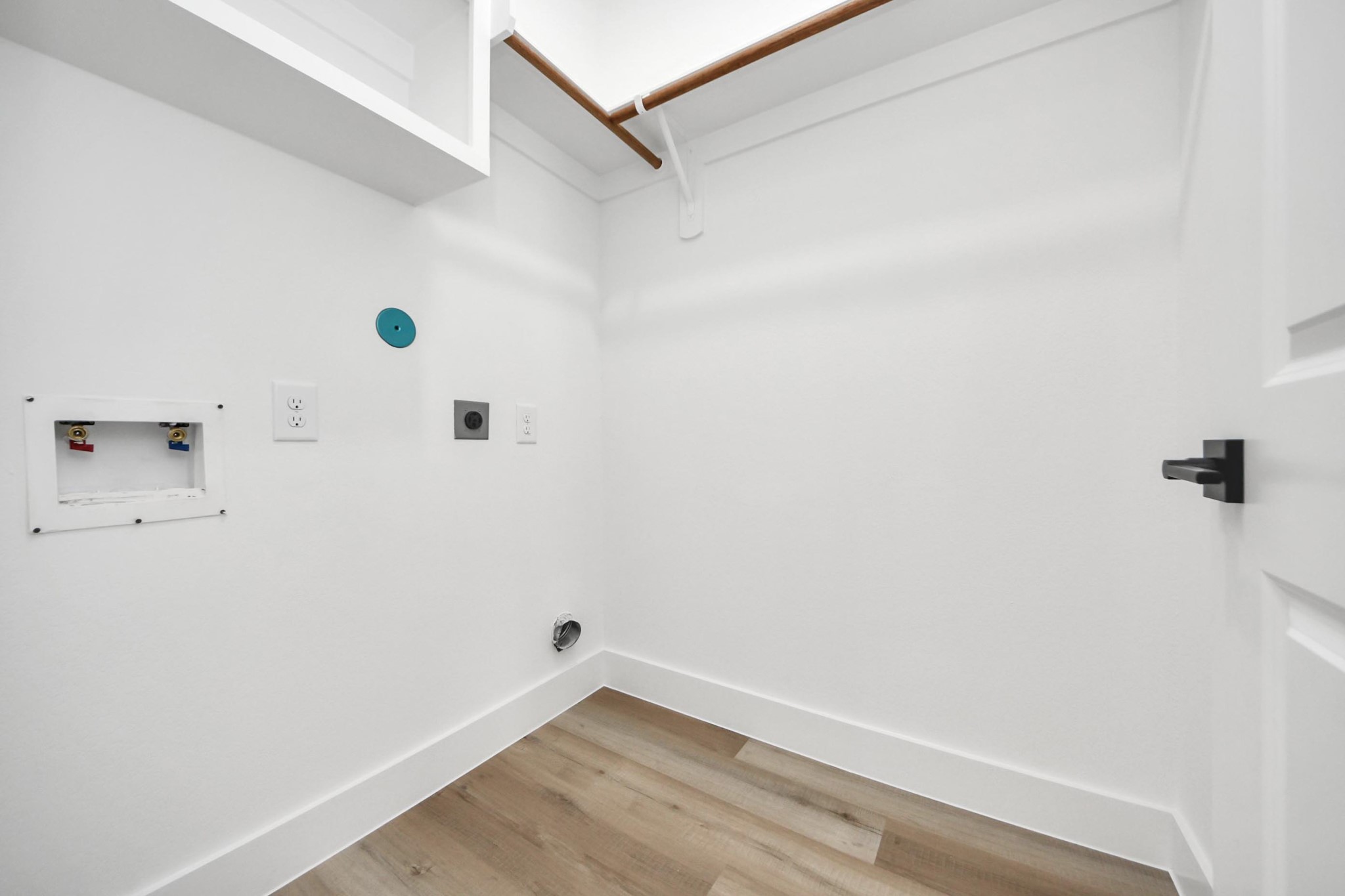 4606 Mallow Street Houston, TX 77051 - Photo 29 of 31 Laundry room with hookups for a washer and dryer. It features white walls, a wooden rod for hanging clothes, and light wood flooring, creating a clean and functional space.