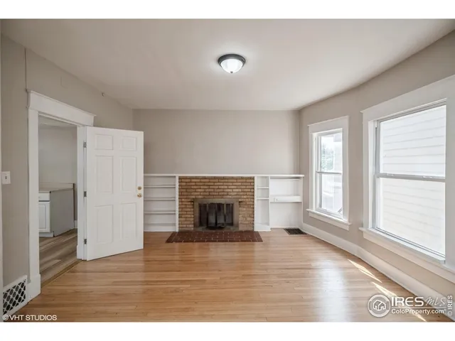 a view of empty room with wooden floor and fireplace