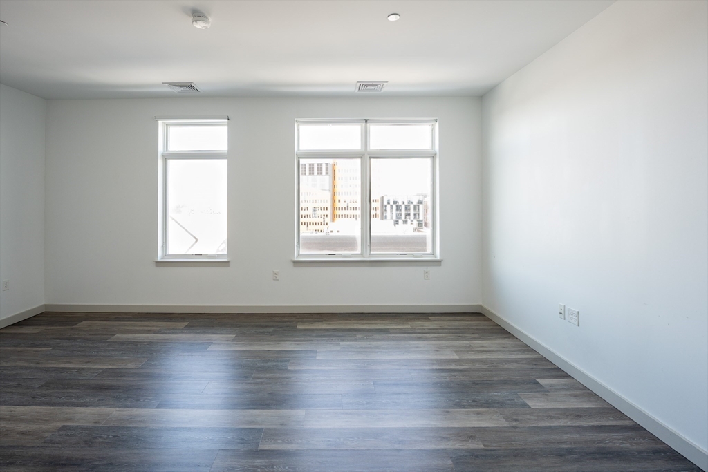 180 Telford Street, Unit 605 Boston, MA 02135 - Photo 9 of 24 an empty room with wooden floor and windows