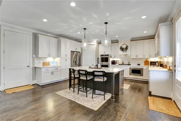 a kitchen with a dining table chairs stainless steel appliances and cabinets