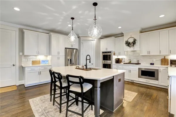 a kitchen with a sink dishwasher a stove and white cabinets with wooden floor