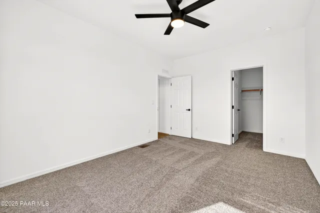 a view of an empty room with wooden floor and a hallway