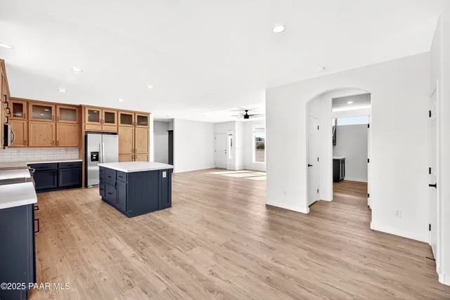 a large kitchen with kitchen island a sink wooden floor and stainless steel appliances