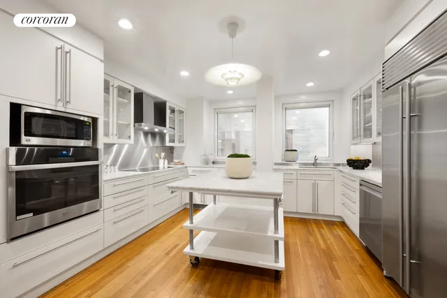 a large kitchen with kitchen island a large counter space stainless steel appliances and cabinets