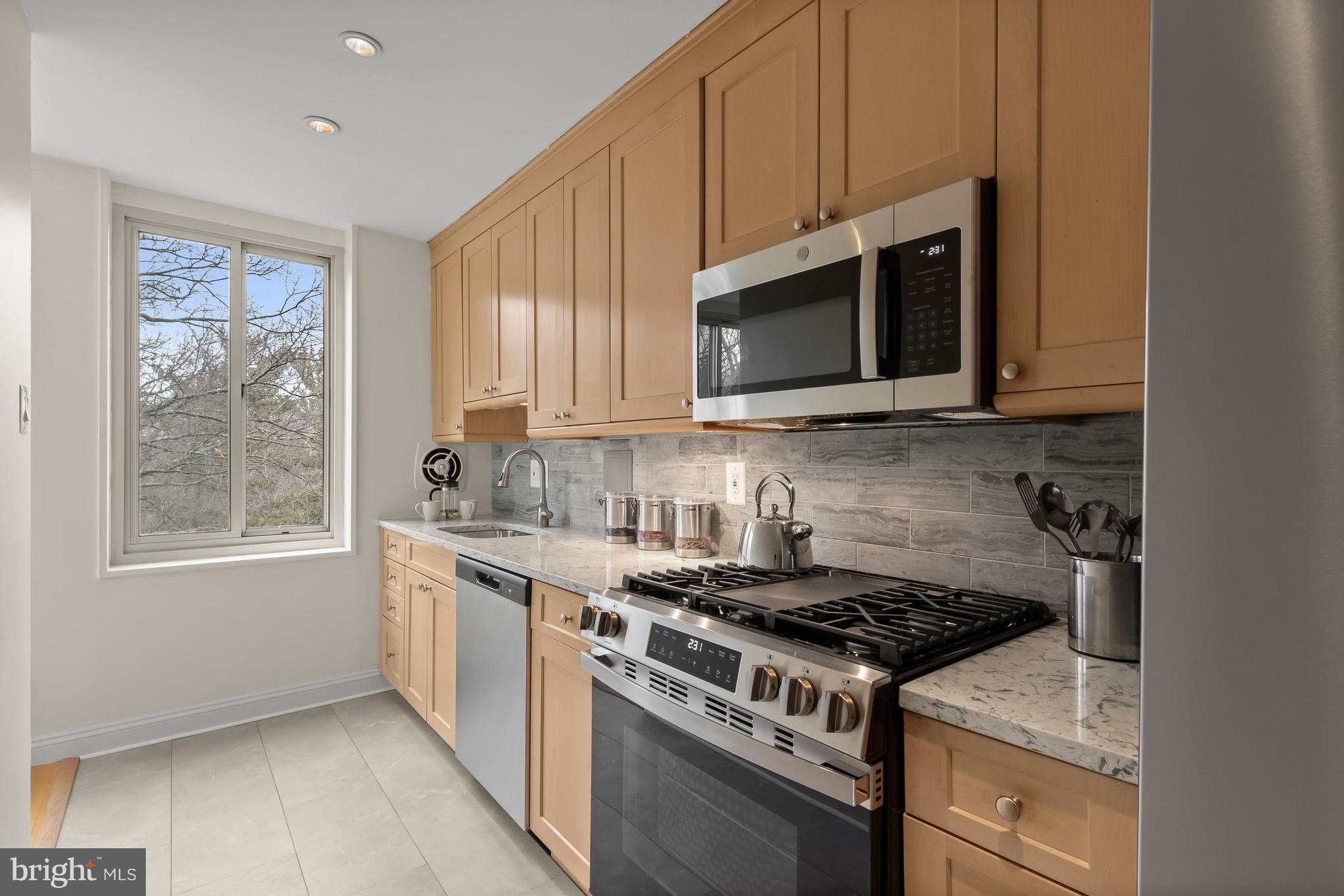 4000 Tunlaw Road Northwest, Unit 1007 Washington, DC 20007 - Photo 14 of 50 a kitchen with stainless steel appliances granite countertop white cabinets granite counter tops and a window