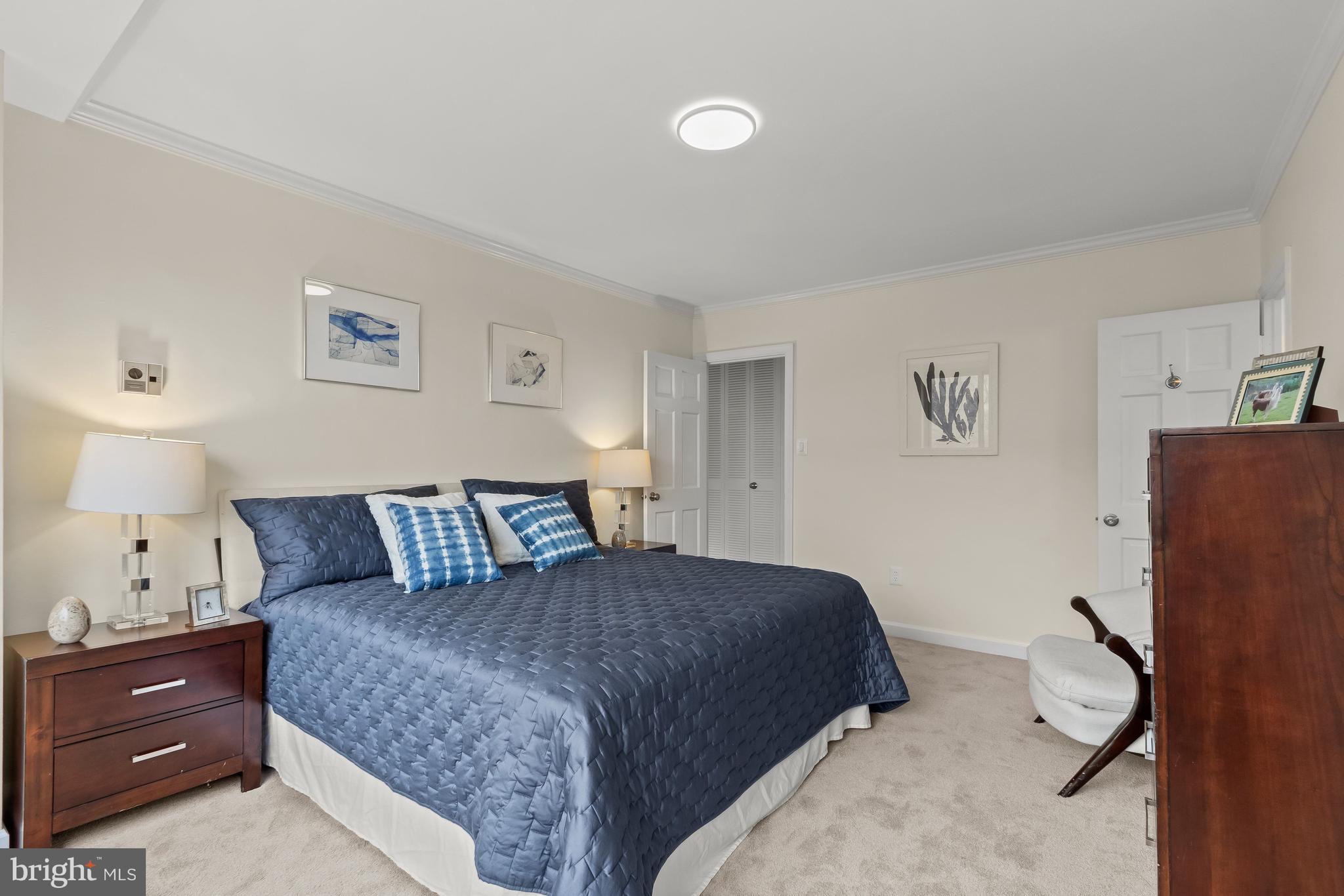 4000 Tunlaw Road Northwest, Unit 1007 Washington, DC 20007 - Photo 19 of 50 a bedroom with a bed and a lamp on dresser