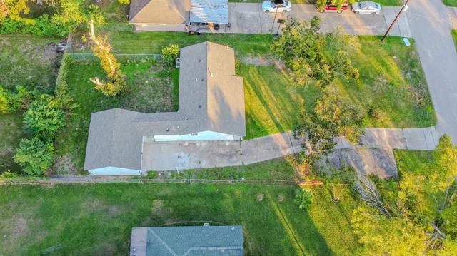 an aerial view of a house with a yard and large trees