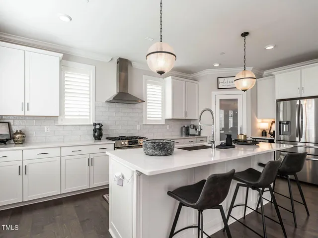 a kitchen with stainless steel appliances a dining table chairs a sink and a window