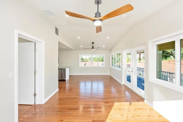 a view of a kitchen and an empty room with wooden floor