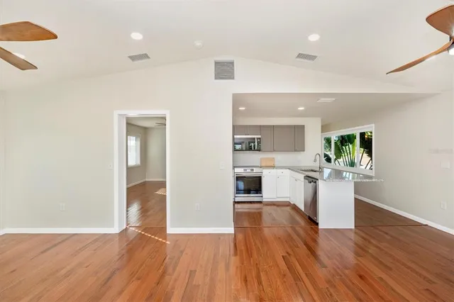 a living room with stainless steel appliances kitchen island a large counter top and wooden floors