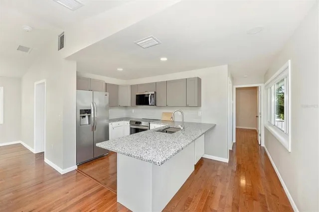 a kitchen with stainless steel appliances granite countertop a refrigerator a stove and a sink with wooden floor