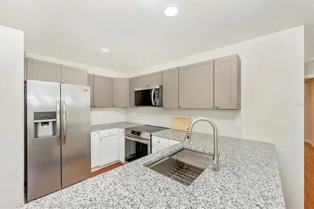 a kitchen with granite countertop a refrigerator and a sink
