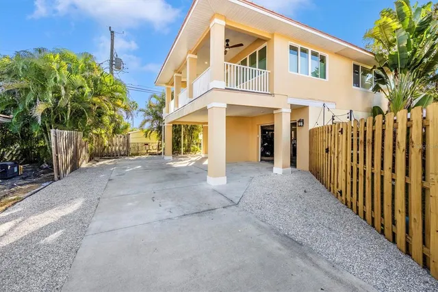 a view of a white house with many windows plants and large trees