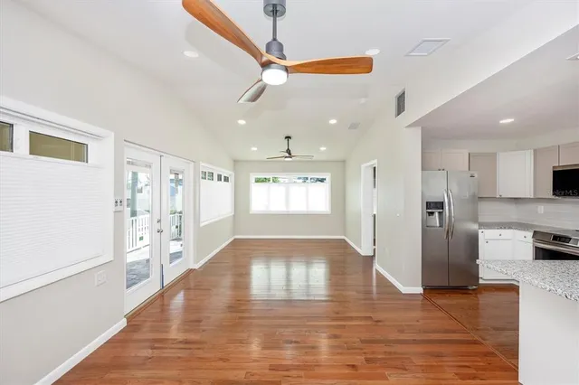 a view of an empty room with wooden floor and a ceiling fan