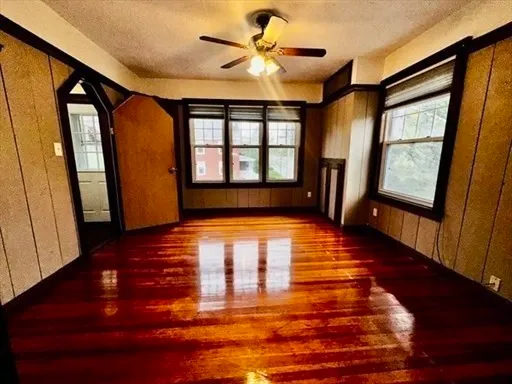 a view of an empty room with window and wooden floor