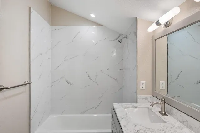 a bathroom with a granite countertop sink toilet and shower