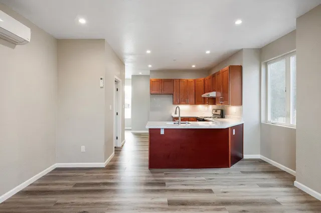 a view of kitchen with stainless steel appliances granite countertop refrigerator oven and white cabinets with wooden floor