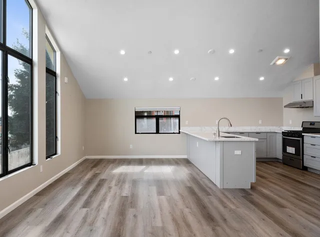 a large kitchen with stainless steel appliances granite countertop a refrigerator a sink a stove and a wooden floors